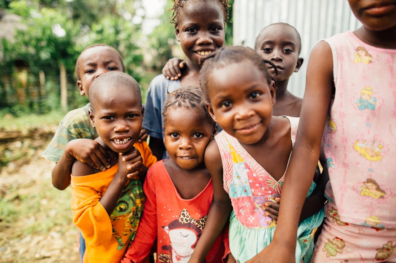 A cheerful group of kids smiling and posing together outdoors, full of happiness and energy.