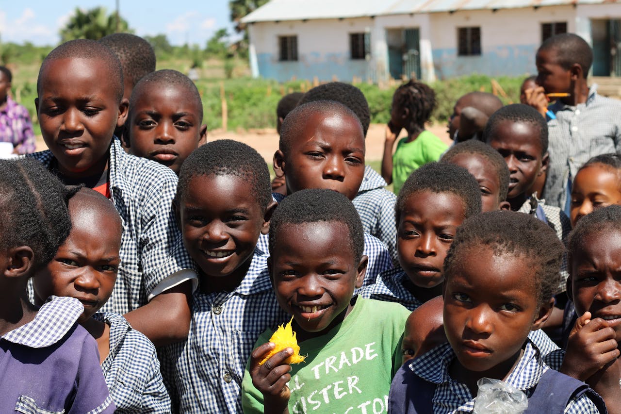 Happy group of children in a Zambian schoolyard on a sunny day.